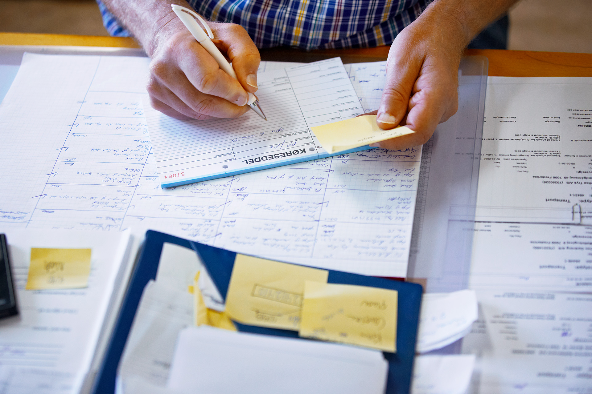 A close up image of hands on a notepad covered with writing and sticky notes.